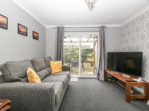uma sala de estar com um sofá e uma televisão de ecrã plano em 8A Rosewood Avenue em Burnham-on-Sea