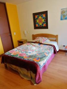 ein Schlafzimmer mit einem Bett mit einer bunten Decke darauf in der Unterkunft Paraíso del Salitre II in Bogotá