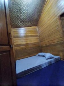 een klein bed in een kamer met houten wanden bij RGA Homestay in Baso