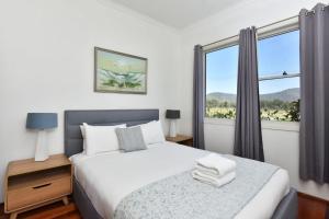 a bedroom with a bed and a large window at Somerville Wines Cottage in Broke