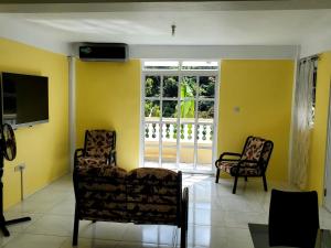 a living room with two chairs and a television at mountain view apartment 2 in Roseau