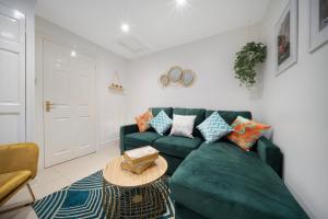 uma sala de estar com um sofá verde e uma mesa em Lovely little house, free on street parking, Smart TV, WiFi em Gloucester