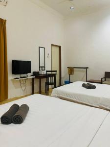 Habitación con 2 camas, escritorio y TV. en ANGGERIK IMPIAN HOTEL -Best for Travellers at Kuala Berang, en Kuala Berang