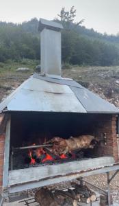 a brick oven with meat and fire in it at Lazer Cardaku guest house in Valbonë