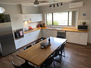 uma cozinha com uma mesa de madeira e uma cozinha com armários brancos em Chesterfarm and Stables em Willyung