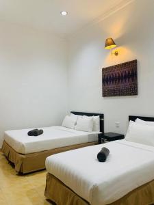 duas camas sentadas uma ao lado da outra num quarto em ANGGERIK IMPIAN HOTEL -Best for Travellers at Kuala Berang em Kuala Berang