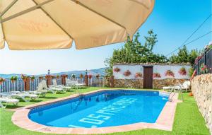 a swimming pool in a yard with chairs and an umbrella at Nice Home In Mecina Bombarn With Outdoor Swimming Pool, Wifi And 2 Bedrooms in Mecina Bombarón
