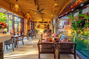 restauracja z basenem, stołami i krzesłami w obiekcie Angel Garden Villa w Hoi An