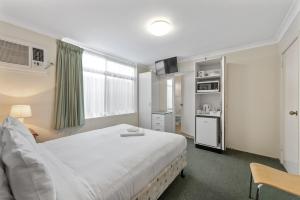 Cet appartement comprend une chambre avec un grand lit blanc et une cuisine. dans l'établissement Paramount Motel, à Brisbane