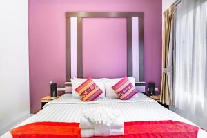1 dormitorio con paredes moradas y 1 cama grande en Cascades Boutique Resort Phuket, en Rawai Beach