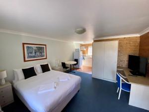 a bedroom with a bed and a desk and a television at Paramount Motel in Brisbane