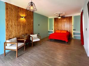 1 dormitorio con cama roja, mesa y sillas en Casa Cielo Rosa, en Ocotlán