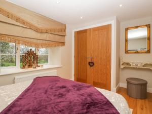 a bedroom with a purple bed and a wooden door at Olive Tree Cottage in Langport
