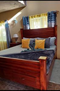 Un dormitorio con una gran cama de madera con almohadas amarillas. en Cambridge mi casa ur casa with pool and beach access en Runaway Bay