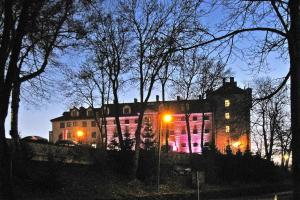 um grande edifício com luzes cor-de-rosa à noite em Apartment right on the lake Ryn em Ryn