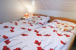 a bed with red flowers on the sheets at Apartment right on the lake Ryn in Ryn