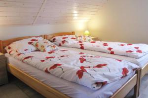 two beds in a bedroom with red flowers on them at Apartment right on the lake Ryn in Ryn