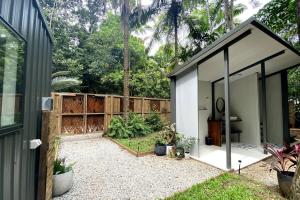 a small white shed with a garden next to a fence at Zen Eco House in Cow Bay