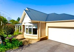 a house with a white garage door in front of it at Cosy Country Cottage in Neerim South