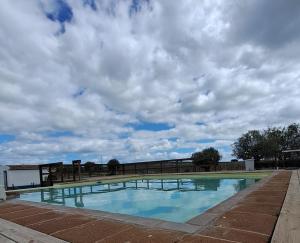 una piscina con un cielo nublado en el fondo en HERDADE DO CORVAL, en Reguengos de Monsaraz
