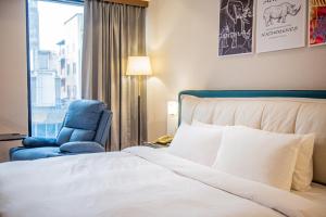 a bedroom with a bed and a chair and a window at Wenpin Hotel - Pier 2 in Kaohsiung