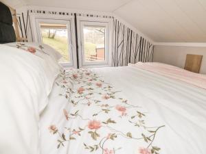 a bedroom with a white bed with pink flowers on it at Oak Tree View in Rhayader