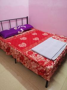 a bed with a red and white quilt on it at Homestay Che Wan Dua in Kuantan