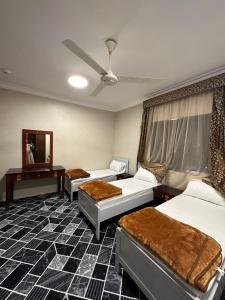 a hotel room with three beds and a mirror at فندق الفخامة اوركيد 2 للغرف والشقق المفروشة in Makkah