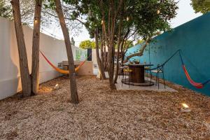 a patio with a hammock and a table and trees at CASA YAXCHE luxury house in downtown Mérida in Mérida