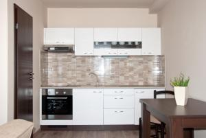 a kitchen with white cabinets and a black oven at Apartmany Fonte in Orechová Potôň