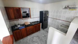 una pequeña cocina con nevera negra y armarios de madera. en Apartamentos en el Rodadero Sur- Ed San José, en Santa Marta