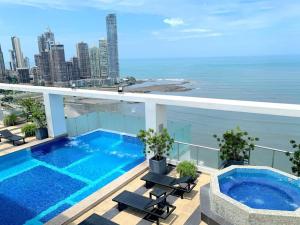a swimming pool on top of a building with the ocean at Apartamento Boutique en Avenida Balboa in Panama City