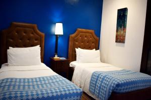 two beds in a room with blue walls at Paradores de Vigan in Vigan
