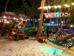 a white beach restaurant with a sign in the sand at White Beach Bungalows in Koh Rong Island