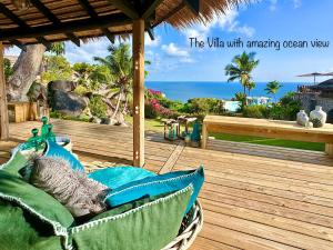 a couch on a deck with an ocean view at Château de feuilles in Baie Sainte Anne