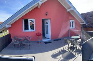 una casa roja con sillas y mesas en un patio en Rooms Jelak, en Velika Gorica