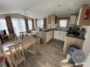 eine Küche und ein Wohnzimmer mit einem Holztisch und Stühlen in der Unterkunft Palm Grove 183 - Golden Palm - Pet friendly, WiFi, central heating, bed linen - Meadow Lakes Caravan & Lodge Hire in Chapel Saint Leonards