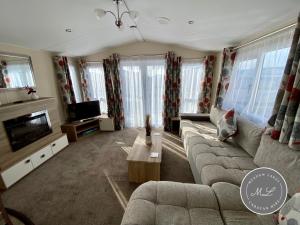 ein Wohnzimmer mit Sofa und Fernseher in der Unterkunft Palm Grove 183 - Golden Palm - Pet friendly, WiFi, central heating, bed linen - Meadow Lakes Caravan & Lodge Hire in Chapel Saint Leonards