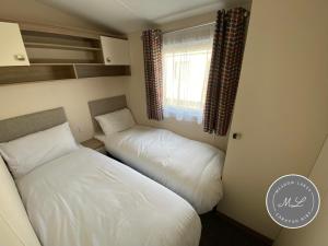 ein kleines Schlafzimmer mit zwei Betten und einem Fenster in der Unterkunft Palm Grove 183 - Golden Palm - Pet friendly, WiFi, central heating, bed linen - Meadow Lakes Caravan & Lodge Hire in Chapel Saint Leonards + 7 Fotos