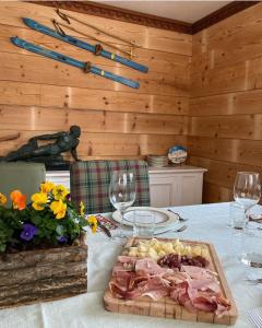 un tavolo con un piatto di carne e bicchieri da vino di APPARTAMENTO CORTINA 1956 a Cortina dʼAmpezzo