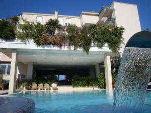 a swimming pool with a fountain in front of a building at Hotel Byron in Rimini