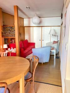 a living room with a table and a red couch at Guesthouse Namaste in Kanazawa