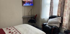 a bedroom with a bed and a chair and a television at Rooms To Let In London in London