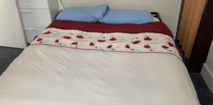 Una cama con una colcha blanca con manzanas rojas. en Rooms To Let In London en Londres