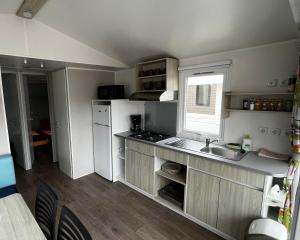uma pequena cozinha com um lavatório e uma janela em Mobil homme proche de la mer em Le Grau-du-Roi
