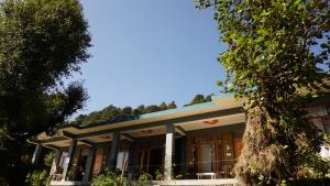 a building with a tree in front of it at Angela's Boutique Homes Dharamkot in Dharamshala