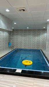 uma piscina com um disco amarelo na água em فيلا قمرية الهدا em Al Hada