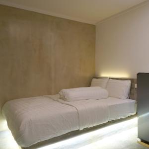 uma cama com lençóis brancos e almofadas num quarto em Djuragan Kamar Mangga Besar em Jacarta