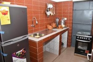 a small kitchen with a sink and a refrigerator at Tranquillité Cotonou in Cotonou
