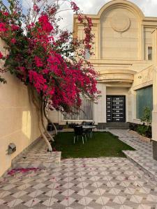 un edificio con un árbol con flores rosas en el patio en سفانه en Unayzah